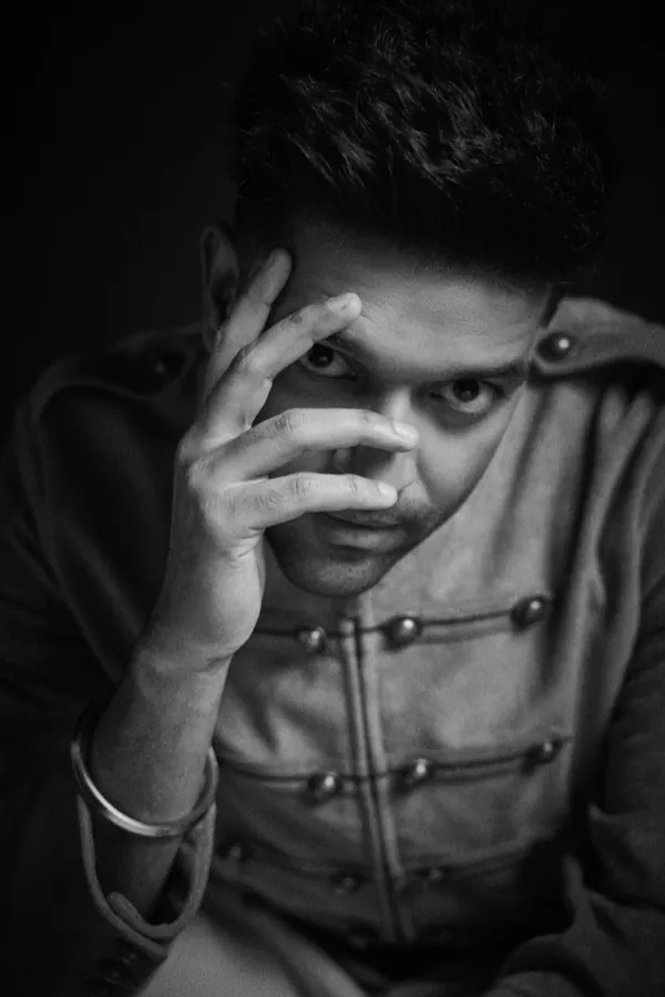 Black-and-white portrait of Guru Randhawa, one hand across his face