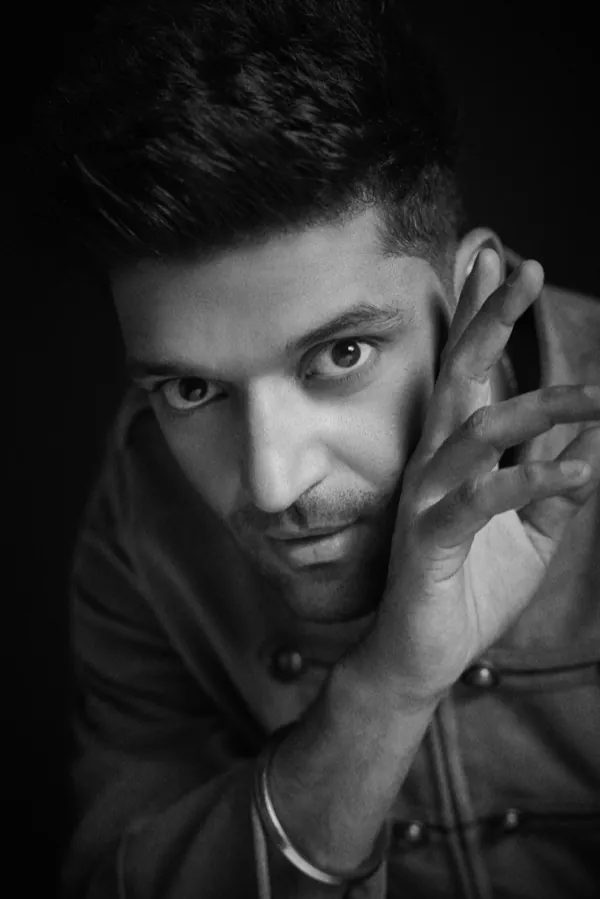 Black-and-white close-up of Guru Randhawa, hands at his face