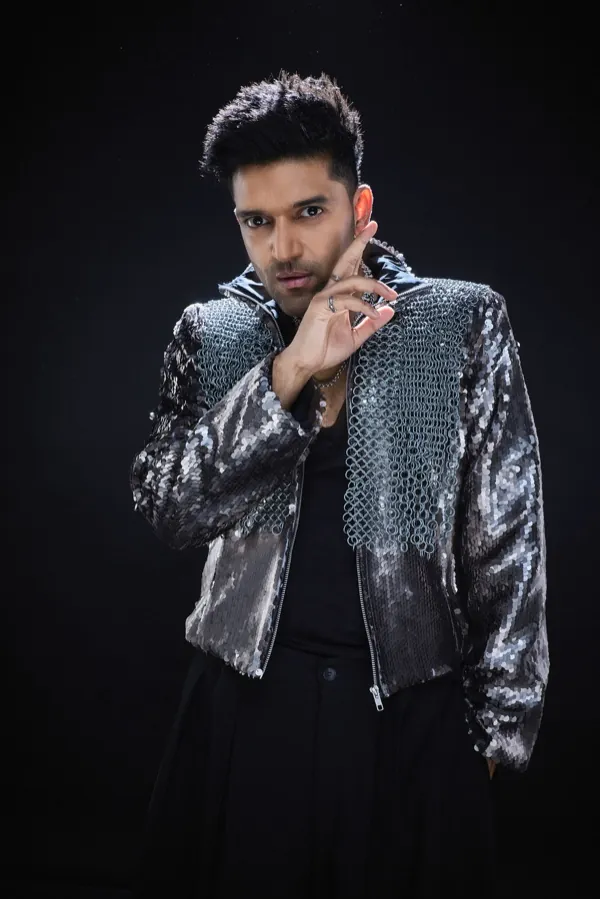 Guru Randhawa glancing sideways, hand raised